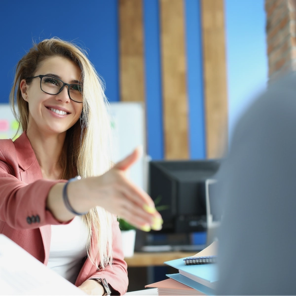 Jeune femme souriante tendant une main décidée.